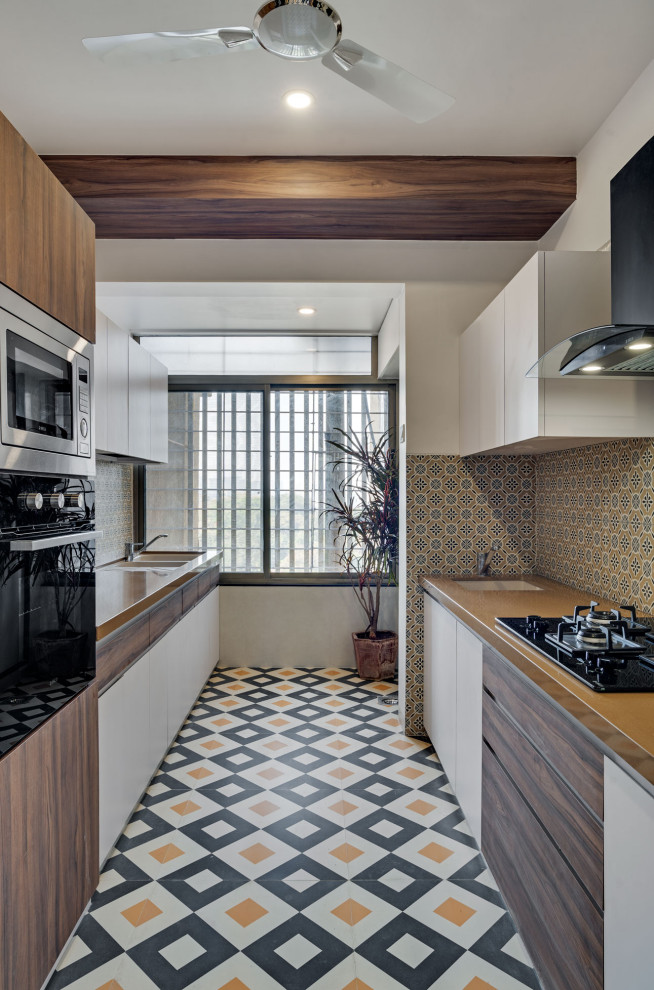 Design ideas for a large contemporary galley kitchen in Bengaluru with an undermount sink, flat-panel cabinets, white cabinets, wood benchtops, multi-coloured splashback, panelled appliances, porcelain floors, no island, multi-coloured floor and brown benchtop.