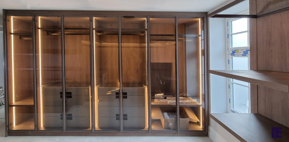 This is an example of a small modern built-in wardrobe in London with open cabinets and brown cabinets.