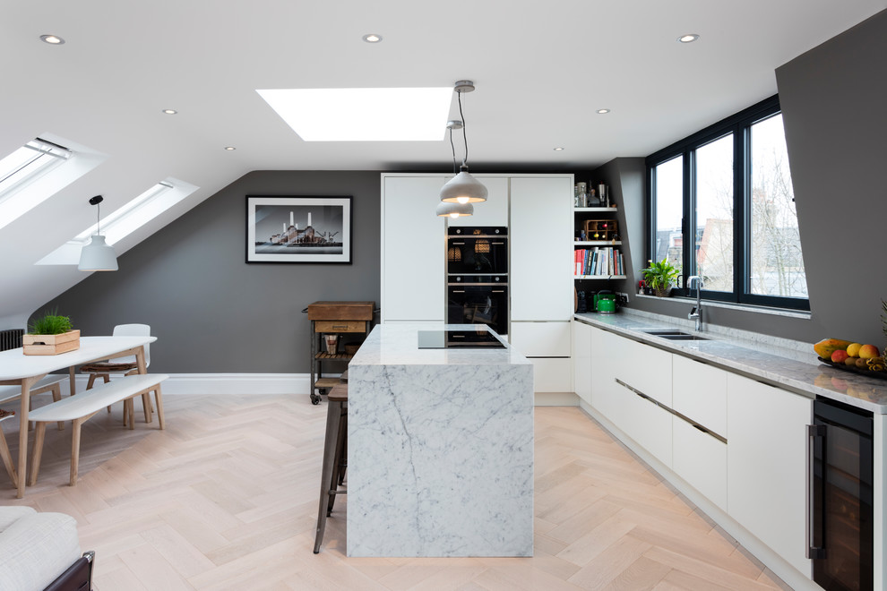 Mid-sized contemporary l-shaped eat-in kitchen in London with flat-panel cabinets, white cabinets, marble benchtops, light hardwood floors, with island and a double-bowl sink.