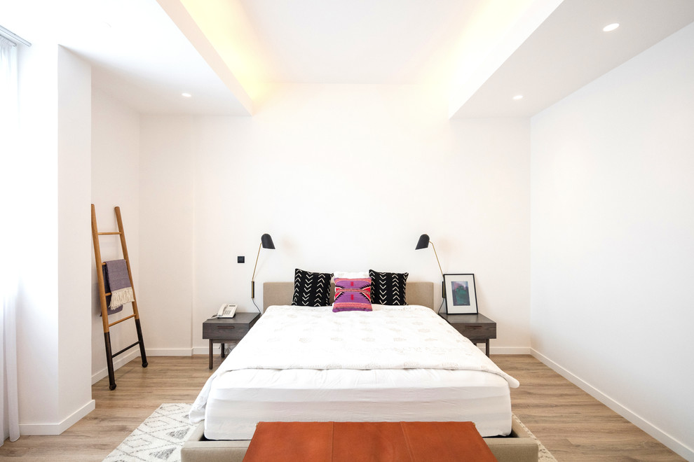 Modern guest bedroom in Los Angeles with white walls, light hardwood floors and beige floor.