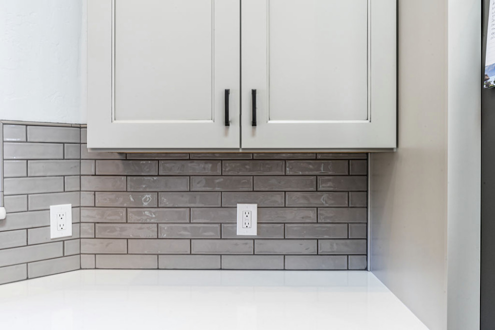 Example of a large transitional u-shaped vinyl floor and gray floor eat-in kitchen design with an undermount sink, shaker cabinets, gray cabinets, quartzite countertops, green backsplash, subway tile backsplash, stainless steel appliances, an island and white countertops