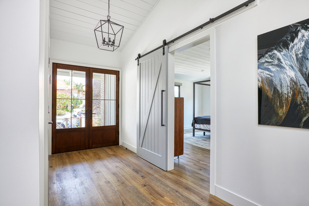 This is an example of a country foyer in Orange County with white walls, vinyl floors, a double front door and a medium wood front door.
