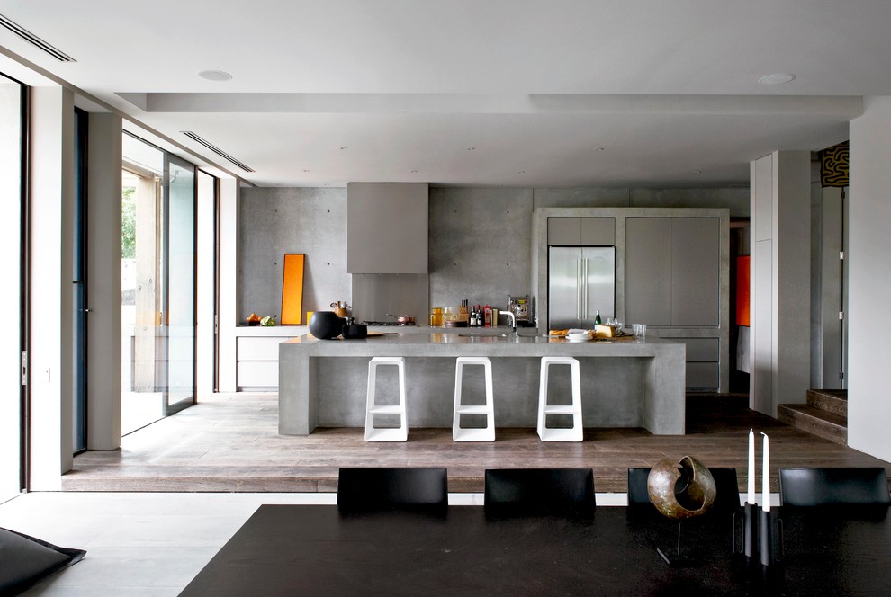 This is an example of a contemporary eat-in kitchen in Melbourne with flat-panel cabinets, grey cabinets, concrete benchtops, cement tile splashback, stainless steel appliances, dark hardwood floors and with island.