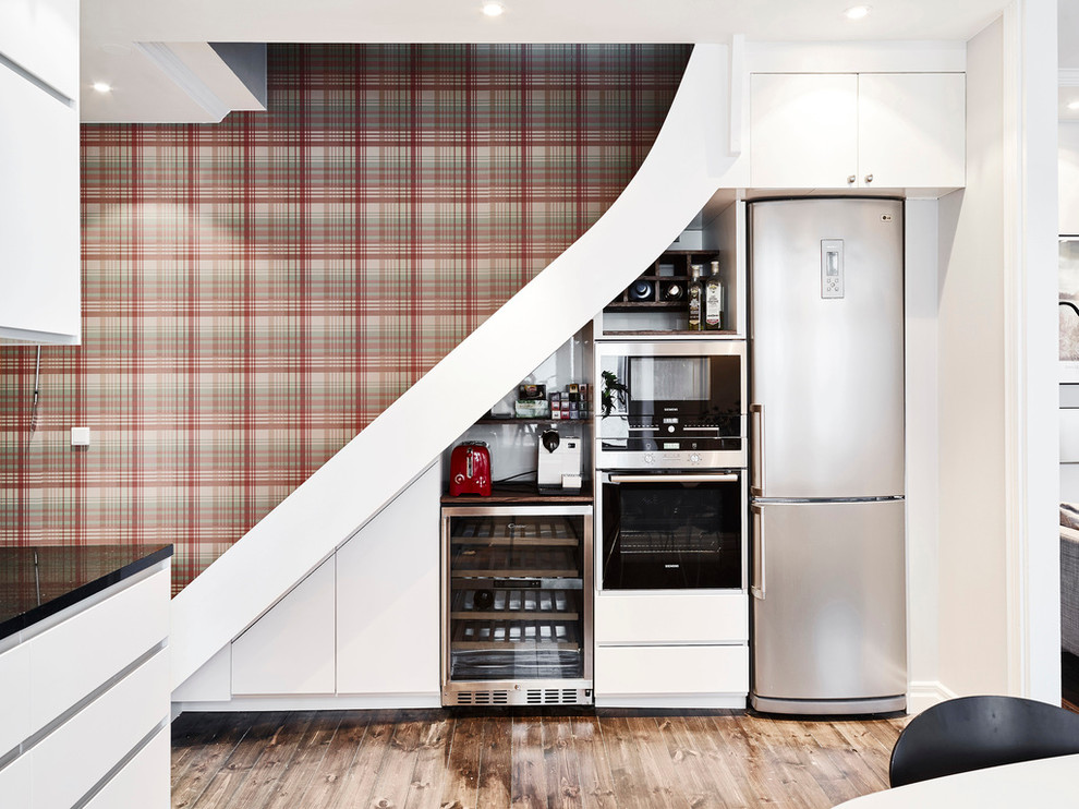 Photo of a scandinavian single-wall eat-in kitchen in Gothenburg with flat-panel cabinets, white cabinets, stainless steel appliances, dark hardwood floors, granite benchtops and no island.