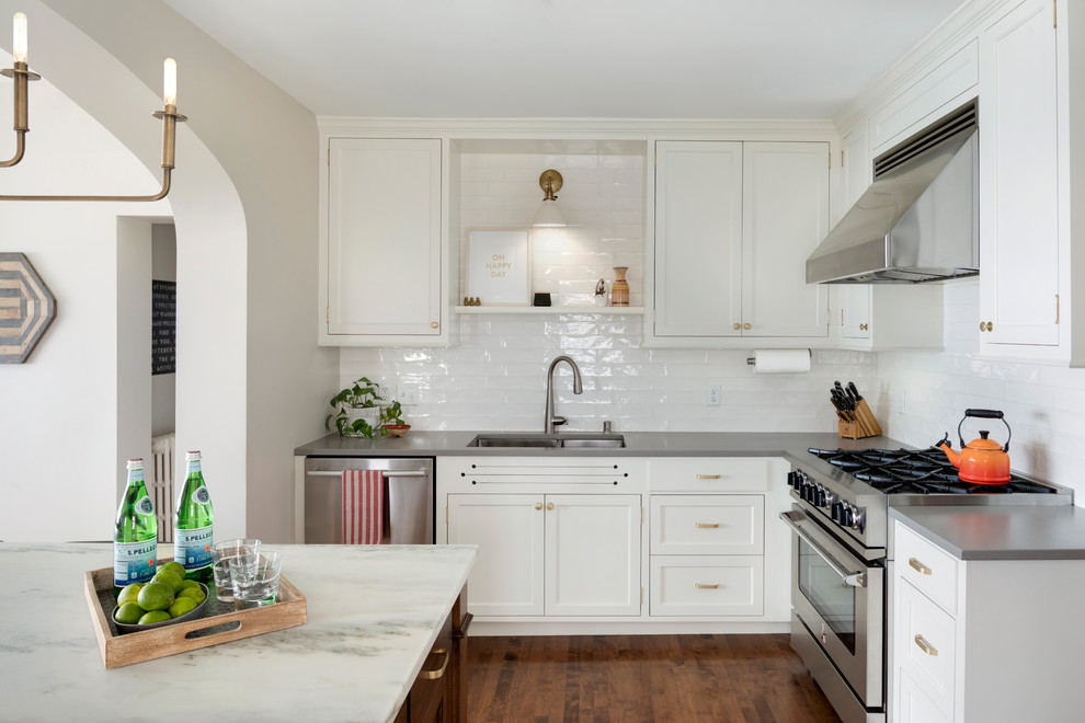 Inspiration for a mid-sized traditional u-shaped open plan kitchen in Minneapolis with an undermount sink, flat-panel cabinets, white cabinets, marble benchtops, white splashback, cement tile splashback, stainless steel appliances, medium hardwood floors and with island.