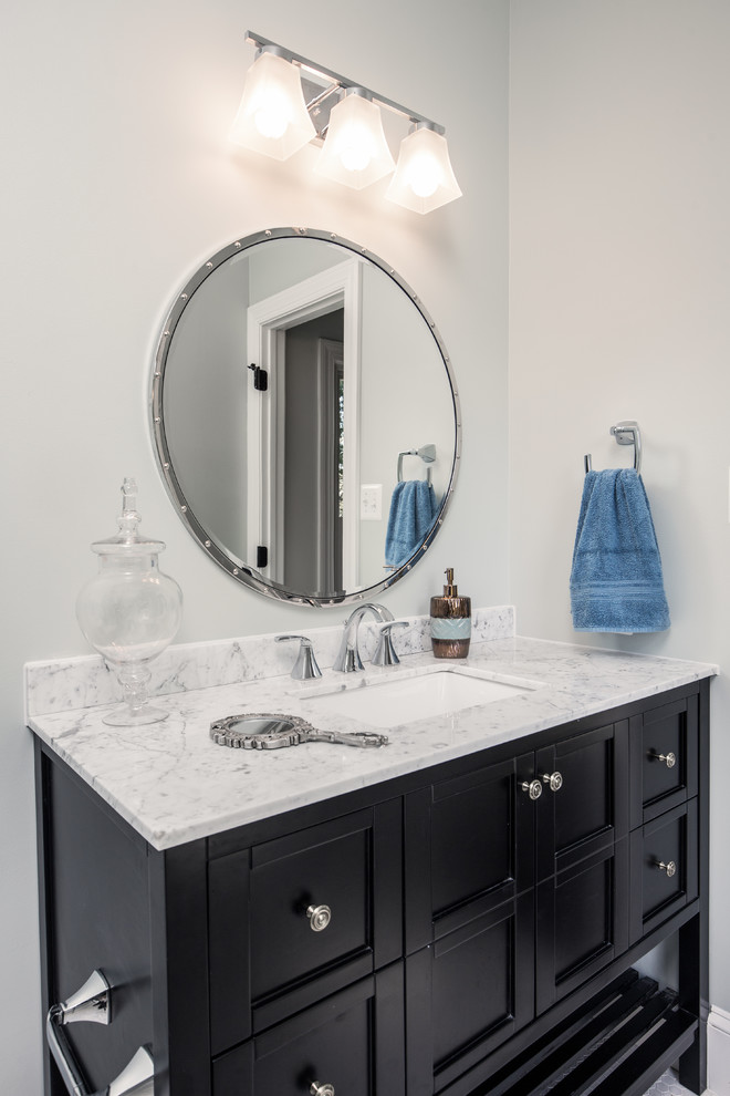 Photo of a mid-sized transitional 3/4 bathroom in DC Metro with shaker cabinets, black cabinets, an alcove shower, a two-piece toilet, white tile, stone tile, grey walls, marble floors, an undermount sink and marble benchtops.