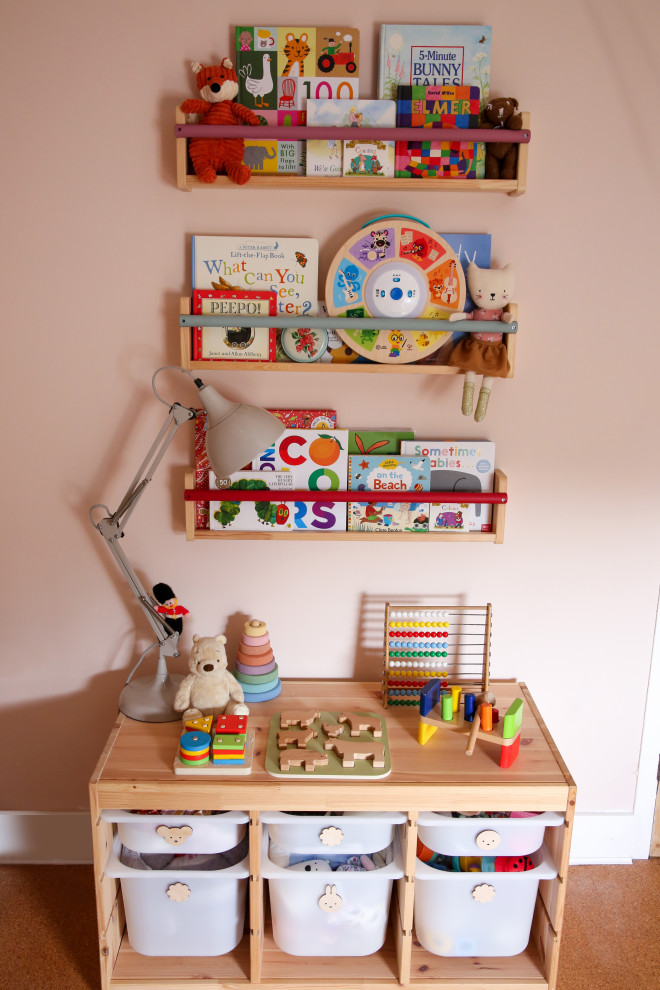 This is an example of a small traditional nursery for girls in Hertfordshire with pink walls and cork flooring.