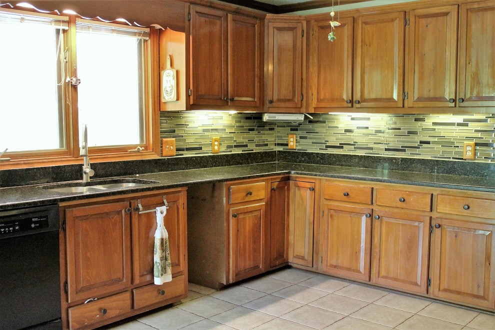 Inspiration for a mid-sized rustic l-shaped ceramic tile enclosed kitchen remodel in Raleigh with a double-bowl sink, raised-panel cabinets, medium tone wood cabinets, granite countertops, multicolored backsplash, glass sheet backsplash, black appliances and no island