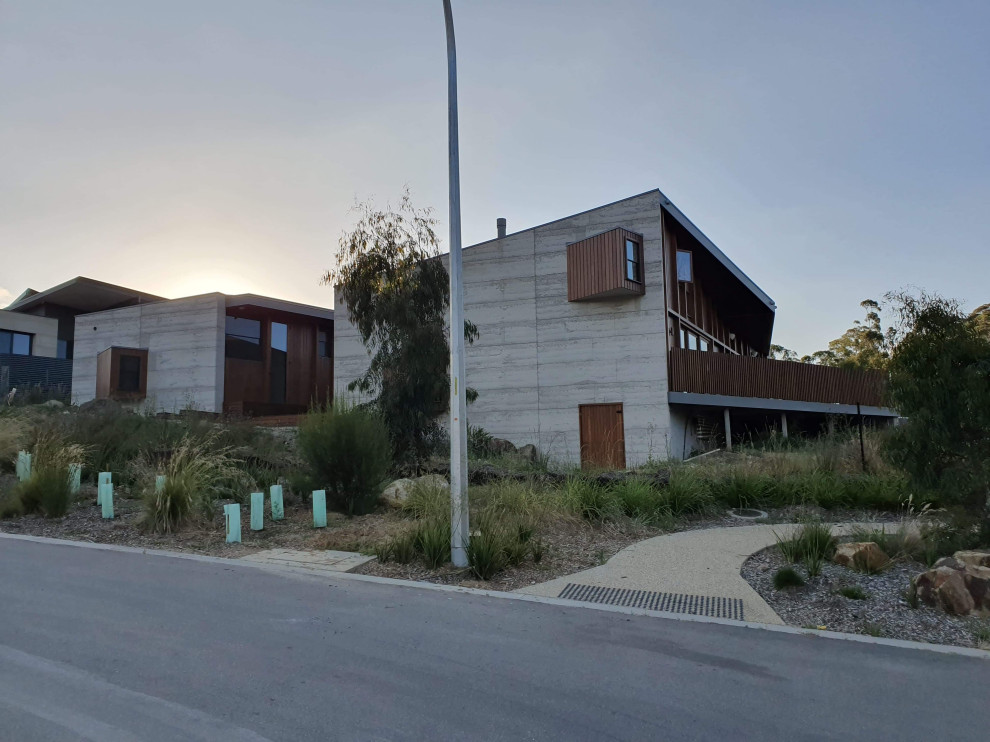 На фото: большой, серый частный загородный дом в стиле лофт с разными уровнями, облицовкой из бетона, серой крышей и отделкой доской с нащельником с