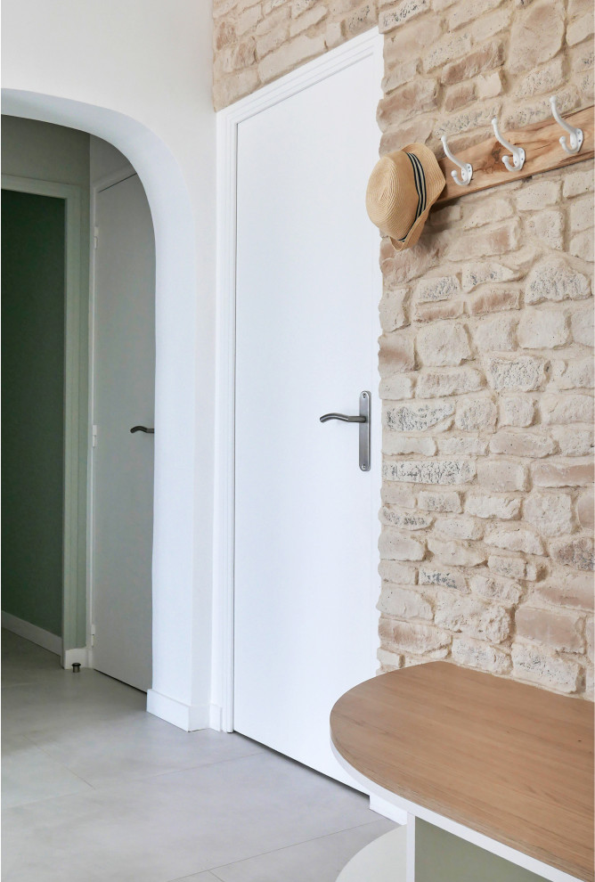 Пример оригинального дизайна: тамбур среднего размера в стиле кантри с бежевыми стенами, полом из керамической плитки, одностворчатой входной дверью, белой входной дверью, серым полом, сводчатым потолком и кирпичными стенами