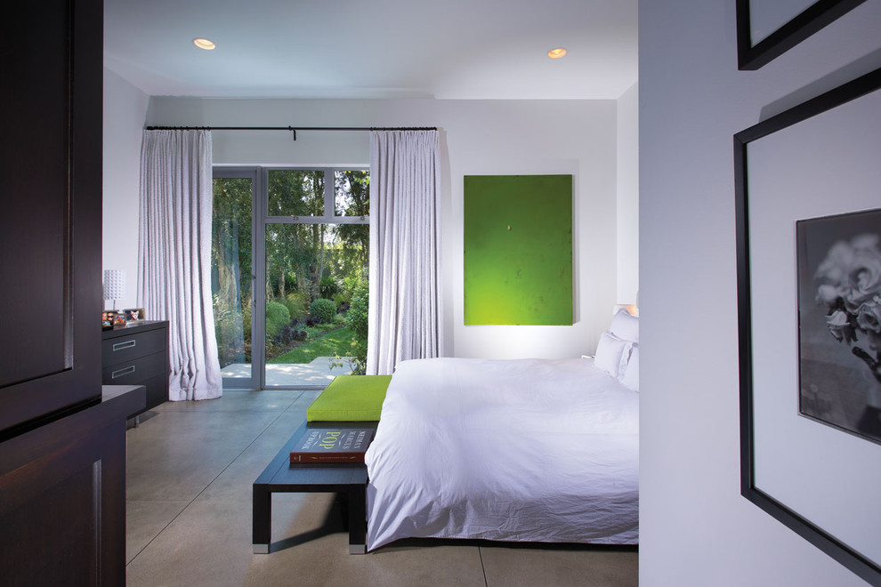 Contemporary bedroom in Orange County with concrete floors and white walls.
