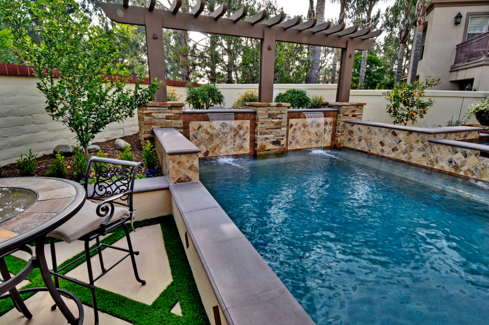 Mid-sized mediterranean backyard rectangular aboveground pool in Orange County with a water feature and concrete slab.