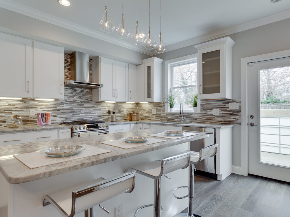 Design ideas for a mid-sized transitional l-shaped kitchen in New York with an undermount sink, shaker cabinets, white cabinets, multi-coloured splashback, mosaic tile splashback, stainless steel appliances, with island, medium hardwood floors and brown floor.