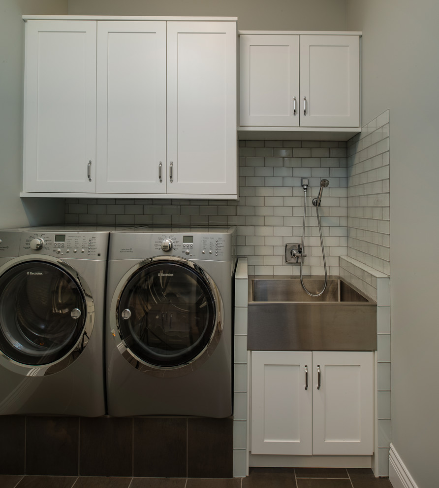 Photo of a mid-sized transitional single-wall utility room in Other with a farmhouse sink, shaker cabinets, white cabinets, granite benchtops, grey walls and a side-by-side washer and dryer.