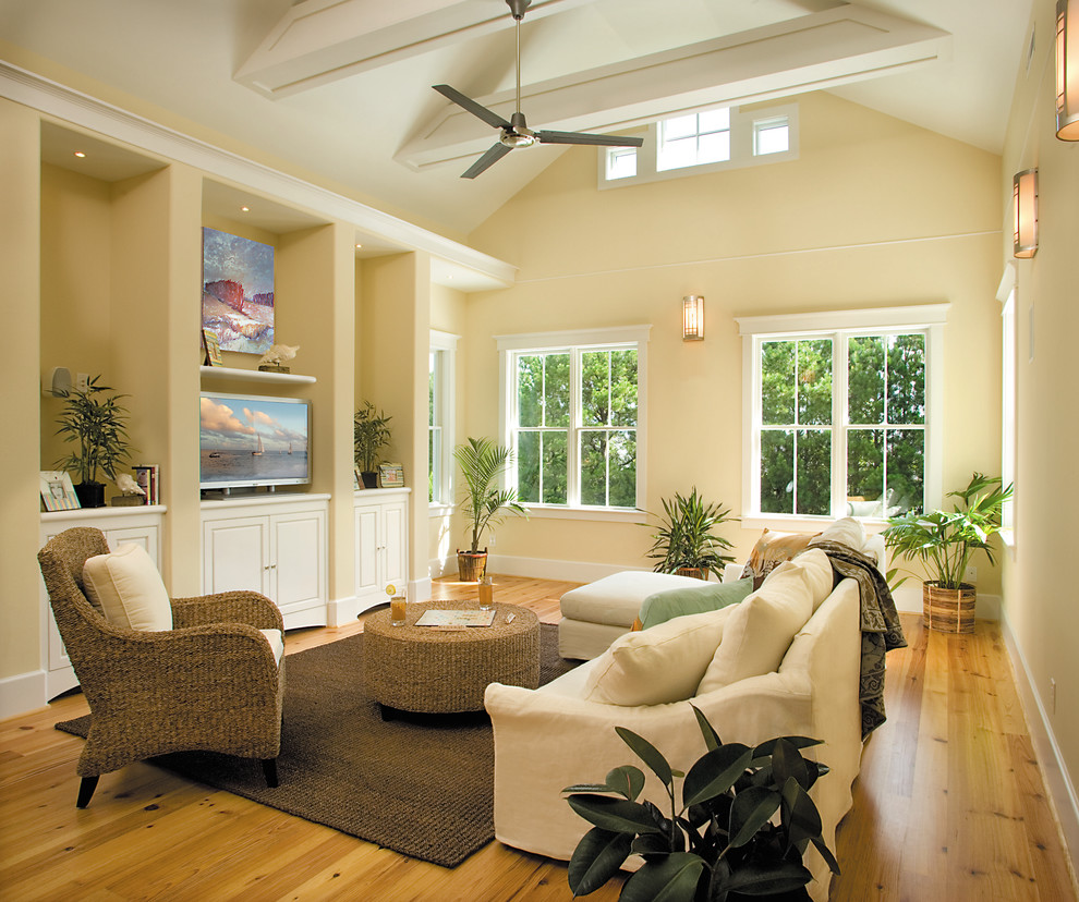 Photo of a beach style family room in Wilmington with beige walls, medium hardwood floors and a freestanding tv.