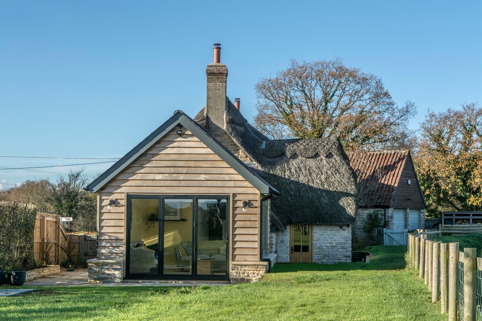 Inspiration for a mid-sized country split-level beige house exterior in Dorset with a gable roof, a mixed roof and mixed siding.
