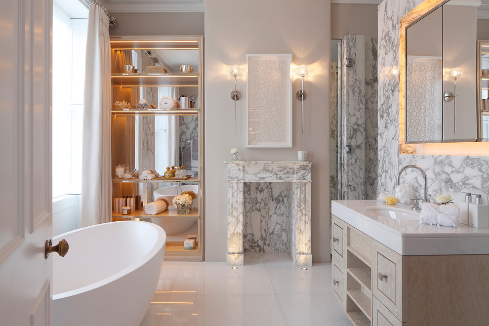 This is an example of a mid-sized transitional bathroom in London with a freestanding tub, a drop-in sink, marble benchtops, beaded inset cabinets and light wood cabinets.