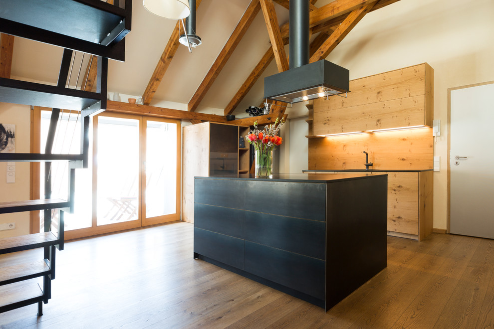Photo of a mid-sized asian galley open plan kitchen in Munich with flat-panel cabinets, brown splashback, timber splashback, medium hardwood floors, with island, brown floor, black benchtop and black cabinets.
