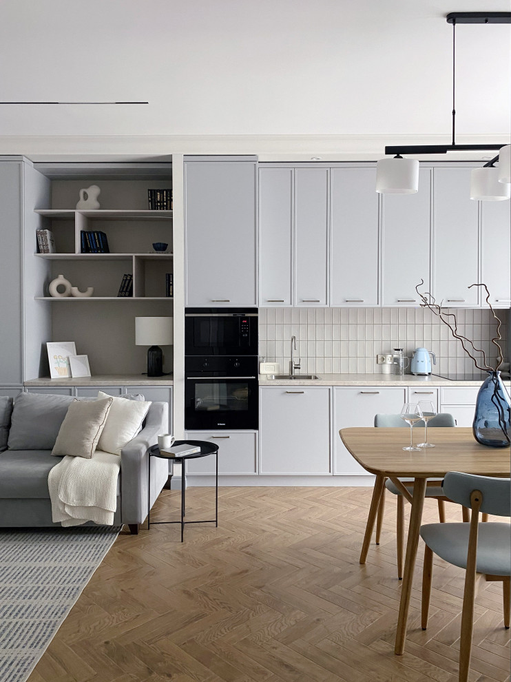Inspiration for a medium sized classic grey and white galley open plan kitchen in Moscow with a built-in sink, beaded cabinets, grey cabinets, laminate countertops, beige splashback, metro tiled splashback, black appliances, porcelain flooring, no island, brown floors and beige worktops.