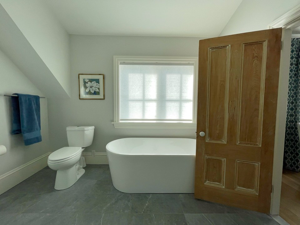 Nordisk inredning av ett mellanstort en-suite badrum, med ett fristående badkar, en toalettstol med separat cisternkåpa, grå väggar, klinkergolv i porslin och grått golv