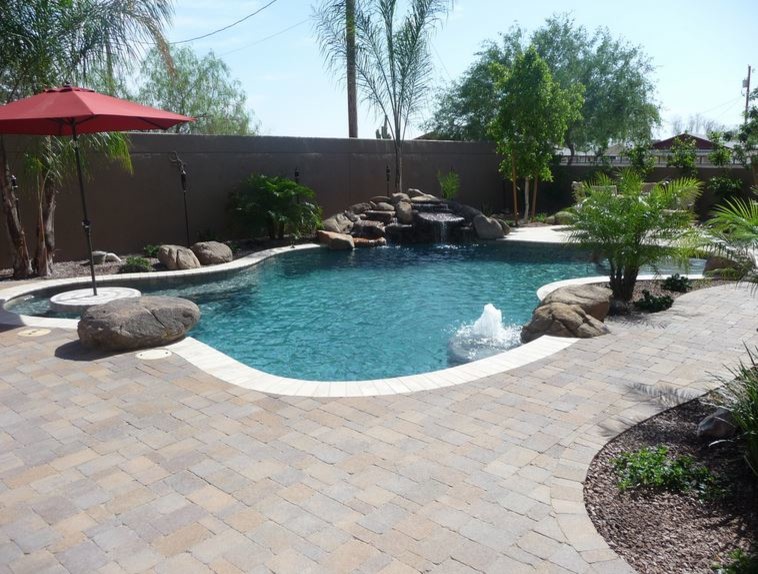 Mid-sized traditional backyard custom-shaped natural pool in Phoenix with a water feature and brick pavers.
