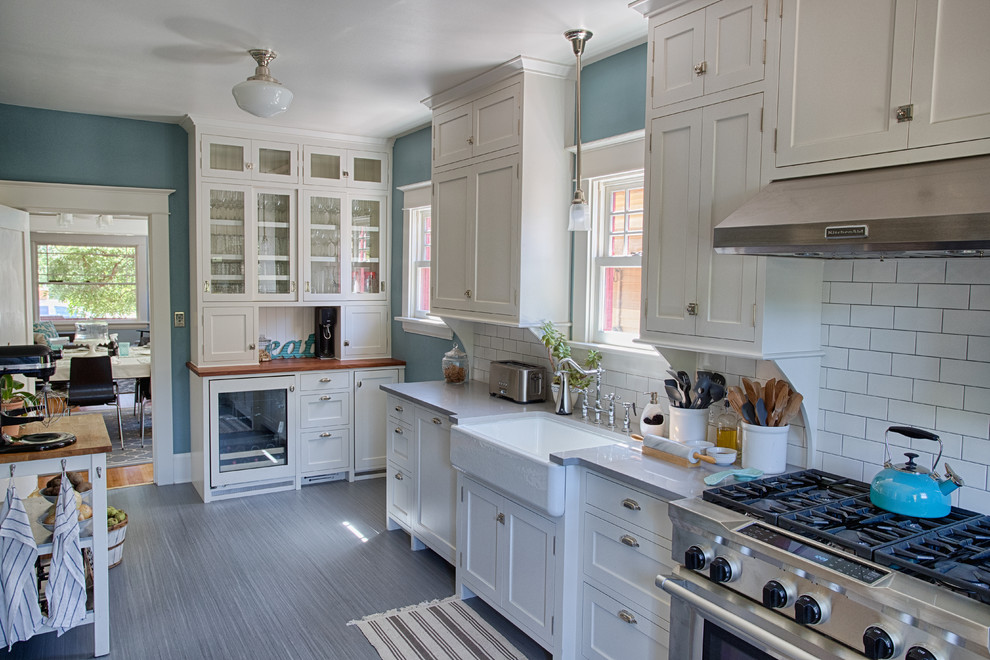 Photo of a mid-sized traditional galley kitchen pantry in Portland with a farmhouse sink, shaker cabinets, white cabinets, quartzite benchtops, white splashback, ceramic splashback, stainless steel appliances, linoleum floors and no island.