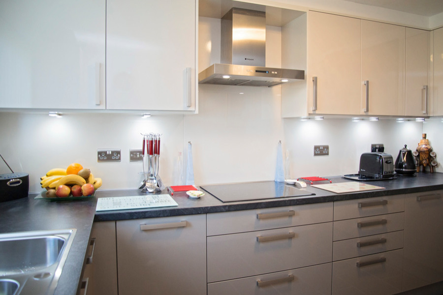 Kleine Moderne Küche in U-Form mit flächenbündigen Schrankfronten, grauen Schränken, Laminat-Arbeitsplatte und schwarzer Arbeitsplatte in Sonstige
