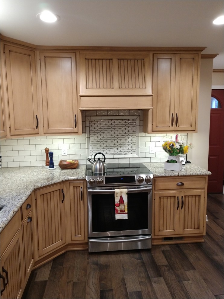 Example of a mid-sized mountain style laminate floor and multicolored floor kitchen design with distressed cabinets, granite countertops, white backsplash, subway tile backsplash, stainless steel appliances, no island and multicolored countertops
