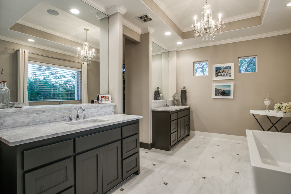 Photo of a large contemporary master bathroom in Dallas with recessed-panel cabinets, black cabinets, a freestanding tub, gray tile, brown walls, limestone floors, a drop-in sink, engineered quartz benchtops, grey floor and grey benchtops.