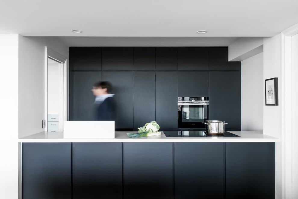 Small modern kitchen in Other with flat-panel cabinets, black cabinets, quartz benchtops, white benchtop and black appliances.