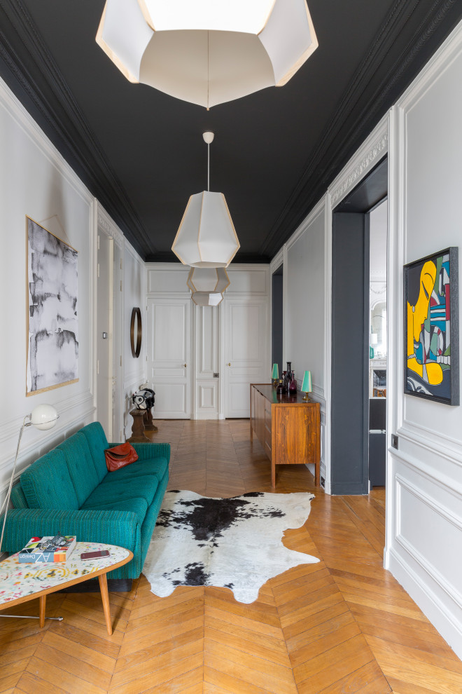 パリにあるお手頃価格の広いコンテンポラリースタイルのおしゃれな玄関ロビー (白い壁、無垢フローリング、白いドア、茶色い床) の写真