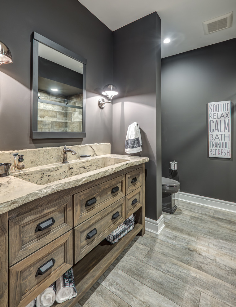 This is an example of a mid-sized country master bathroom in Columbus with flat-panel cabinets, distressed cabinets, a one-piece toilet, grey walls, light hardwood floors, an integrated sink, grey floor, a curbless shower, gray tile, slate and beige benchtops.