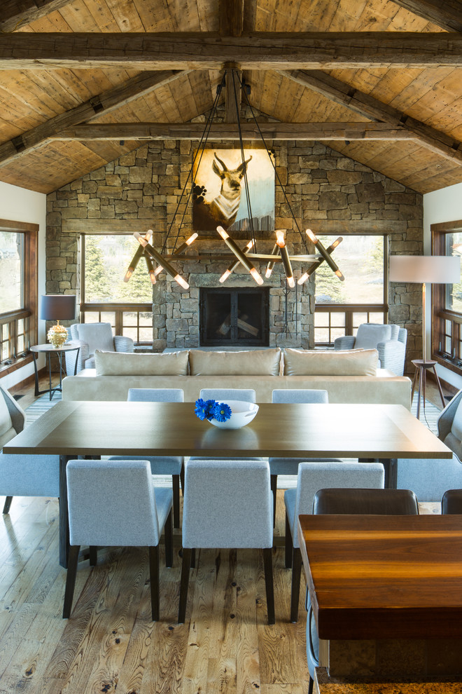 Design ideas for a country open plan dining in Other with white walls, medium hardwood floors, a standard fireplace and a stone fireplace surround.