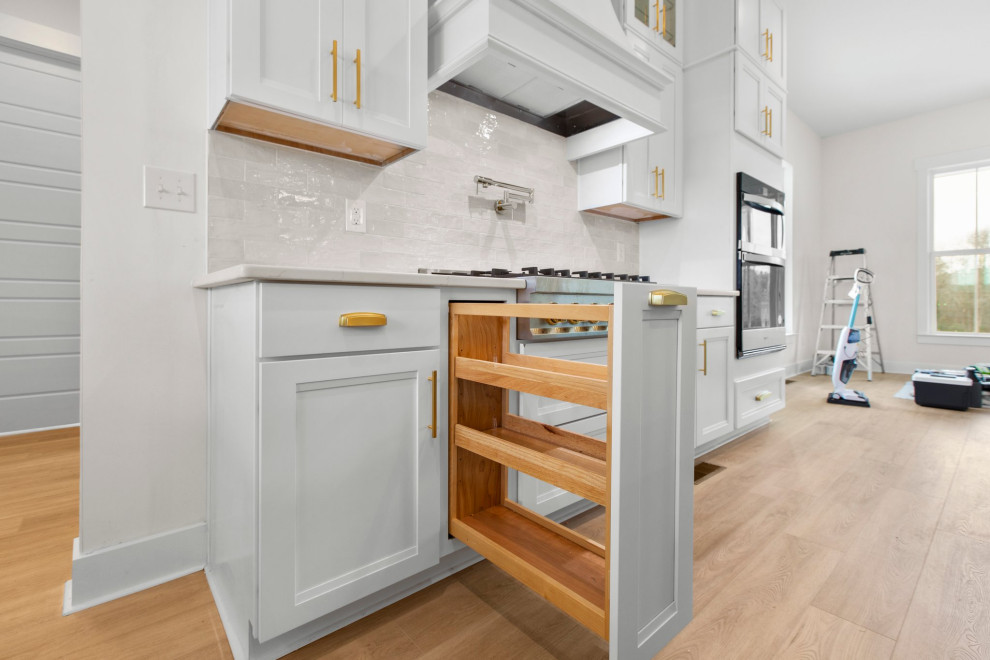Open concept kitchen - large transitional l-shaped open concept kitchen idea in Richmond with a farmhouse sink, recessed-panel cabinets, quartz countertops, white backsplash, stainless steel appliances, an island and white countertops