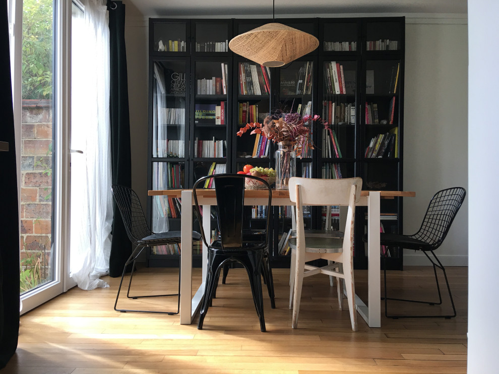 Immagine di una piccola sala da pranzo aperta verso il soggiorno eclettica con parquet chiaro