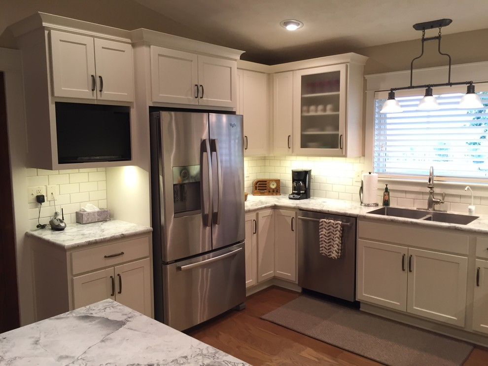 Eat-in kitchen - mid-sized transitional u-shaped medium tone wood floor eat-in kitchen idea with an integrated sink, shaker cabinets, white cabinets, laminate countertops, white backsplash, subway tile backsplash, stainless steel appliances and a peninsula