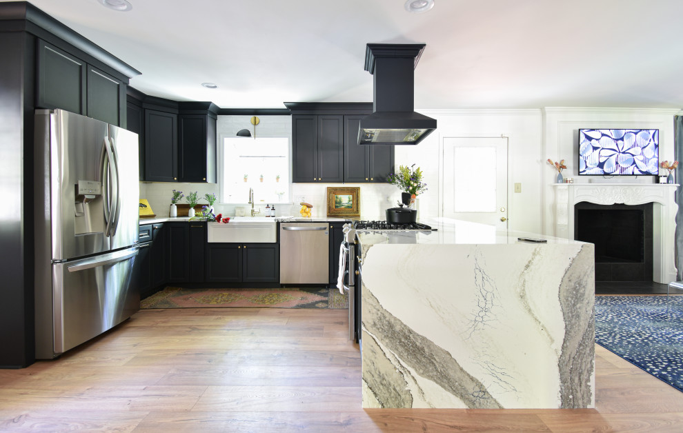 Open concept kitchen - mid-sized transitional u-shaped laminate floor open concept kitchen idea with a farmhouse sink, black cabinets, quartzite countertops, white backsplash and a peninsula