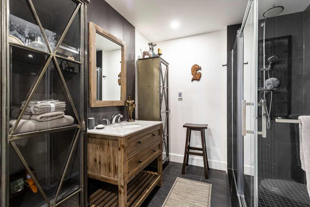 This is an example of a large contemporary shower room bathroom in Montreal with open cabinets, medium wood cabinets, a corner shower, a one-piece toilet, porcelain tiles, porcelain flooring, a submerged sink, marble worktops, black floors, a sliding door, white worktops, a single sink, a freestanding vanity unit, black tiles and white walls.