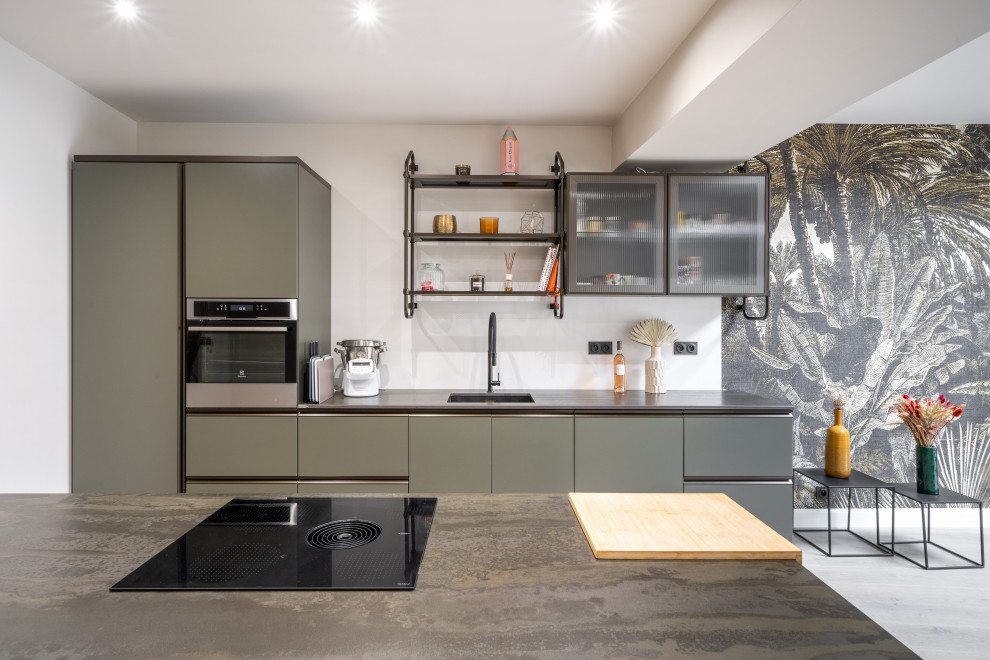 Exempel på ett stort industriellt brun linjärt brunt kök med öppen planlösning, med en integrerad diskho, luckor med glaspanel, gröna skåp och en köksö