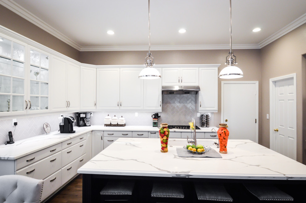 Photo of a mid-sized contemporary u-shaped eat-in kitchen in Los Angeles with an undermount sink, raised-panel cabinets, white cabinets, quartz benchtops, white splashback, porcelain splashback, stainless steel appliances, laminate floors, with island, brown floor and white benchtop.