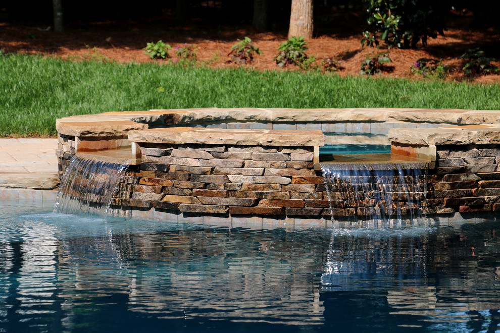 Hot tub - large rustic backyard concrete paver and custom-shaped natural hot tub idea in Raleigh