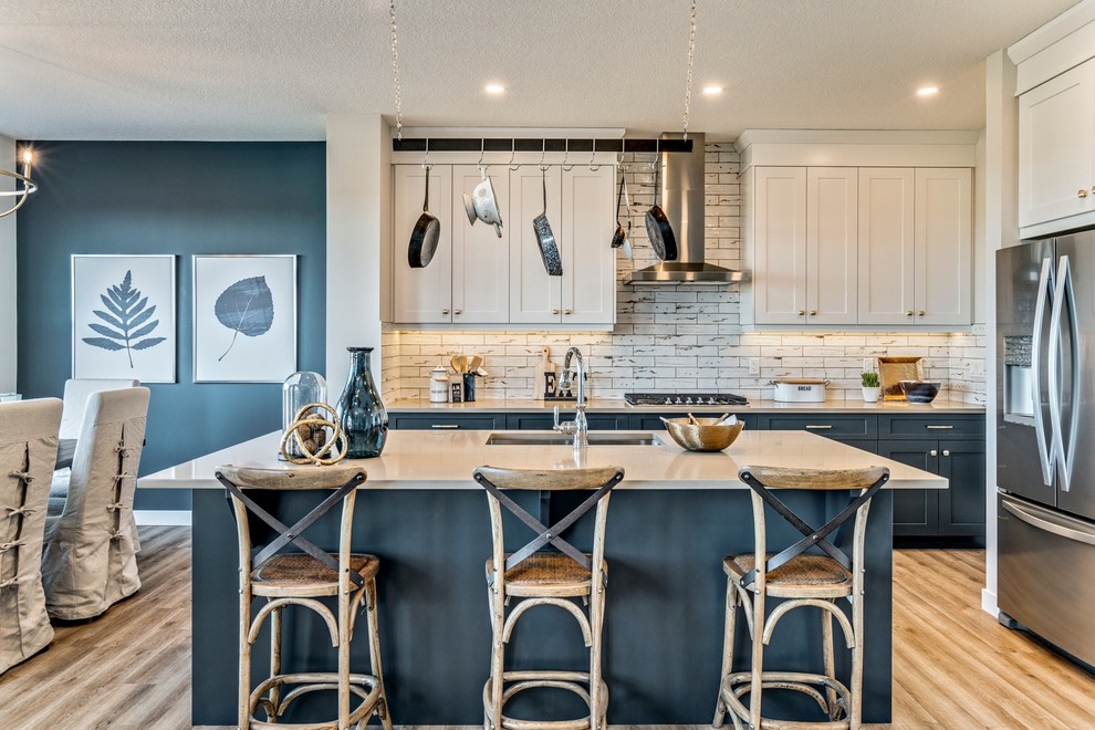 Photo of a beach style eat-in kitchen in Calgary with an undermount sink, shaker cabinets, blue cabinets, beige splashback, stainless steel appliances, with island, beige floor and beige benchtop.