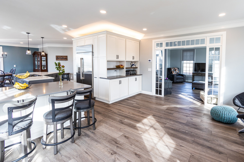 Kitchen - large transitional vinyl floor and brown floor kitchen idea in Baltimore with an undermount sink, shaker cabinets, white backsplash, porcelain backsplash, stainless steel appliances, an island and white countertops