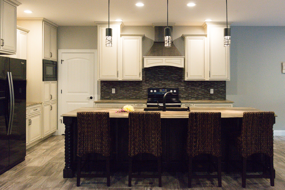 Large transitional l-shaped ceramic tile eat-in kitchen photo in Chicago with an undermount sink, raised-panel cabinets, dark wood cabinets, marble countertops, brown backsplash, glass tile backsplash, black appliances and an island