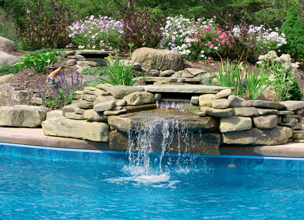 This is an example of a large traditional backyard pool in New York with a water feature and concrete pavers.