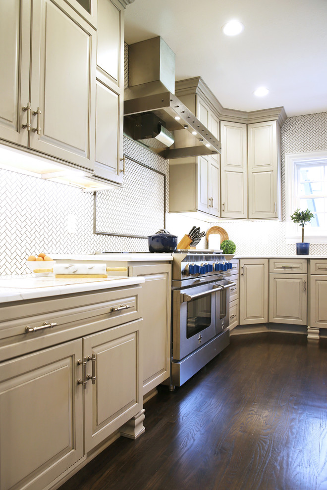 Large transitional l-shaped dark wood floor and brown floor enclosed kitchen photo with raised-panel cabinets, white backsplash, ceramic backsplash, stainless steel appliances and an island