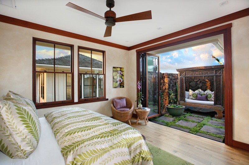 Large tropical guest bedroom in Hawaii with beige walls and light hardwood floors.