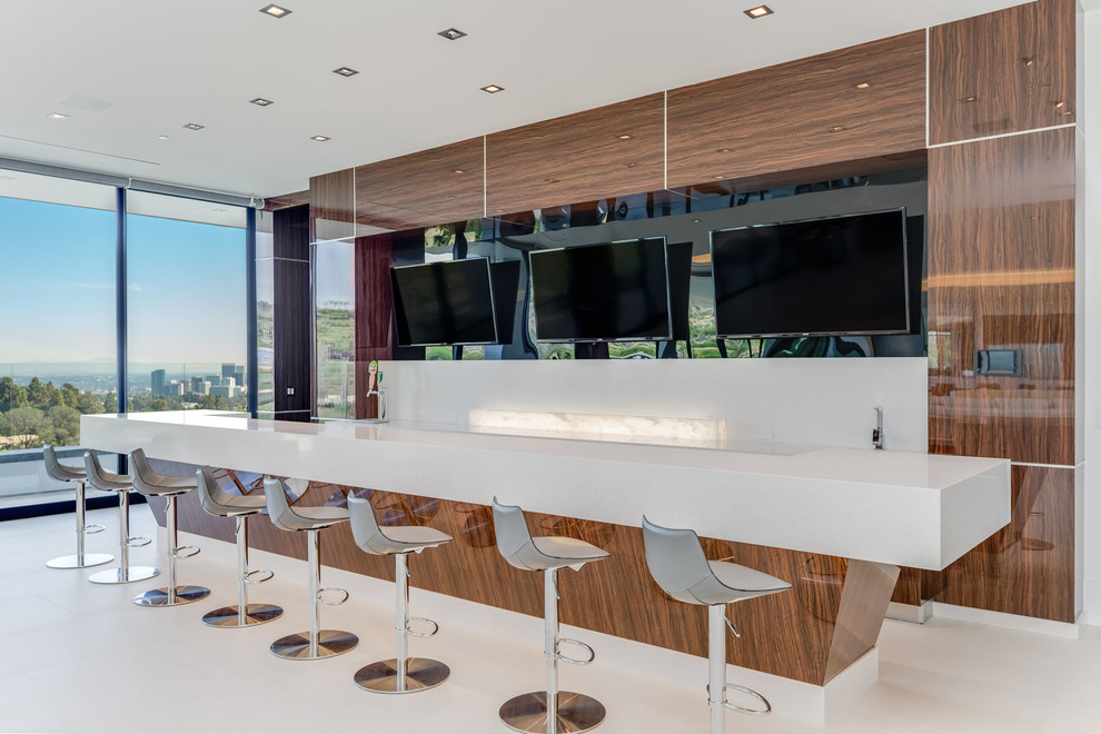 Inspiration for a large modern u-shaped home bar in Los Angeles with a drop-in sink, recessed-panel cabinets, medium wood cabinets, quartz benchtops, white splashback, engineered quartz splashback, porcelain floors, white floor and white benchtop.