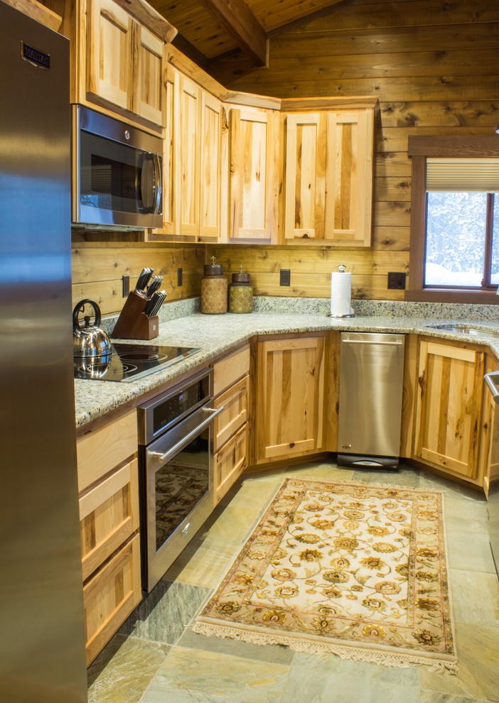 Example of a mid-sized mountain style u-shaped slate floor and gray floor eat-in kitchen design with flat-panel cabinets, medium tone wood cabinets, granite countertops, stainless steel appliances, an island and an undermount sink