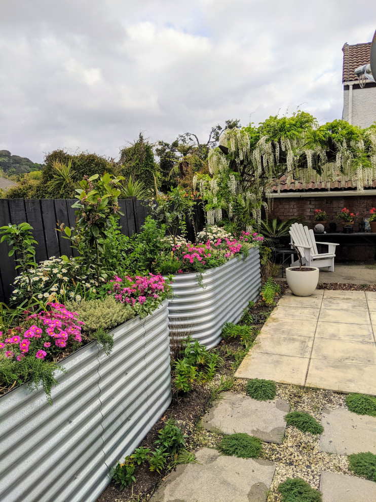 This is an example of a small country courtyard full sun garden in Auckland with with raised garden bed and concrete pavers.
